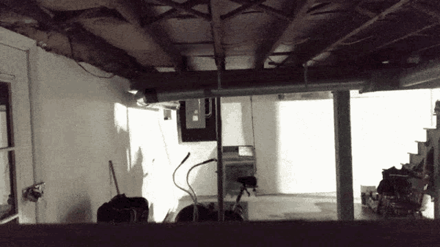 a black and white photo of a basement with a staircase visible