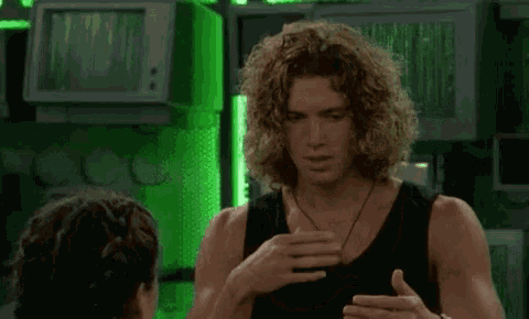 a man with long curly hair is talking to a woman in a room with green lights .