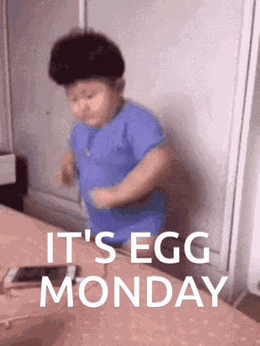 a little boy is standing in front of a table with the words it 's egg monday written on it