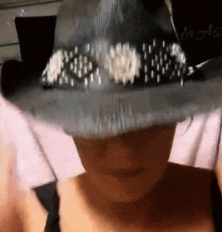 a woman wearing a hat with pearls on it covering her face
