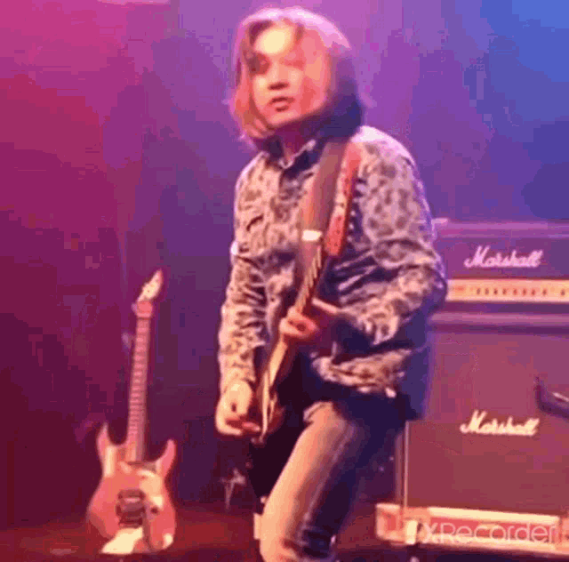 a man is playing a guitar on a stage in front of a marshall amplifier