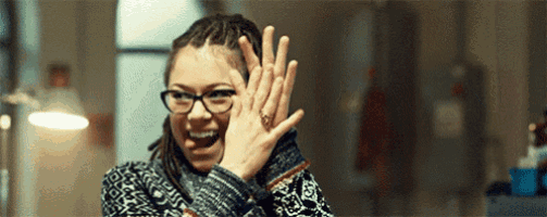 a woman wearing glasses is covering her face with her hands and smiling .