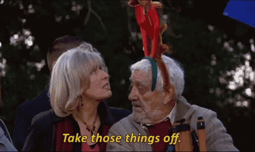a man and a woman are standing next to each other and the man is wearing a reindeer hat .