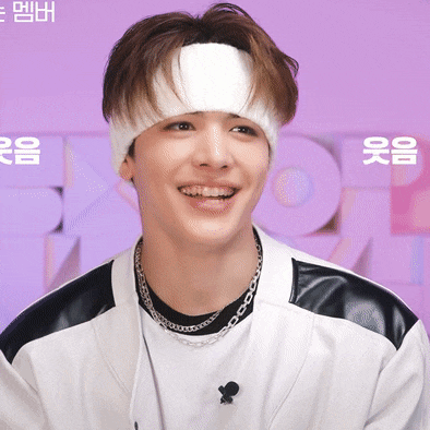 a young man wearing a headband and a necklace smiles