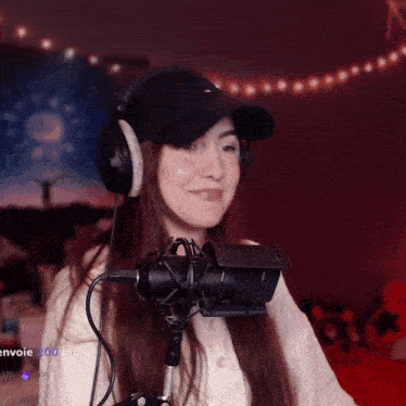 a woman wearing headphones and a hat stands in front of a microphone with the words envoie 200 bits visible