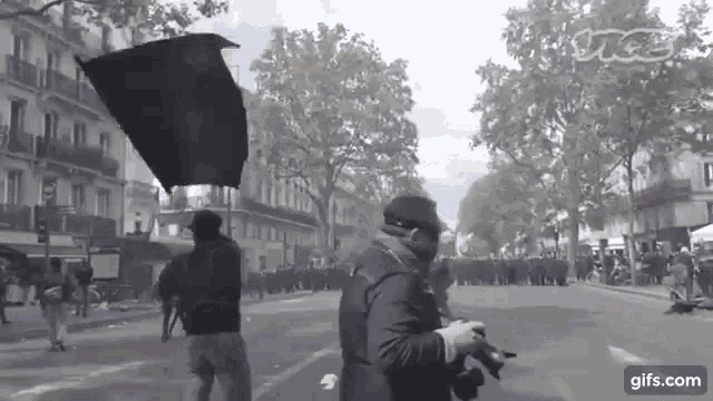 a man in a mask is holding a camera while walking down a street .