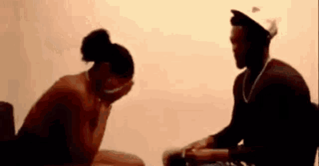 a man and a woman are sitting next to each other and the woman is covering her face with her hands .