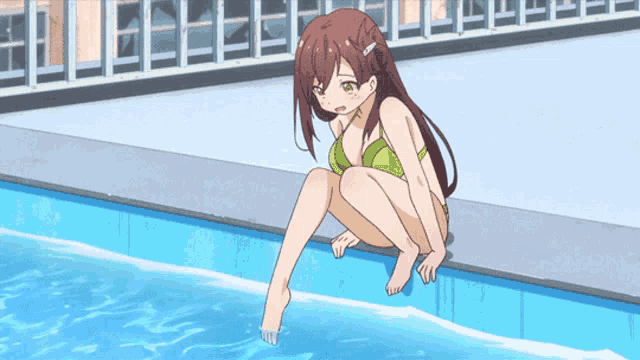 a girl in a green bikini is sitting on the edge of a pool