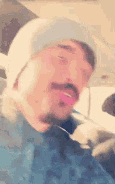 a man with a tongue sticking out is wearing a beanie