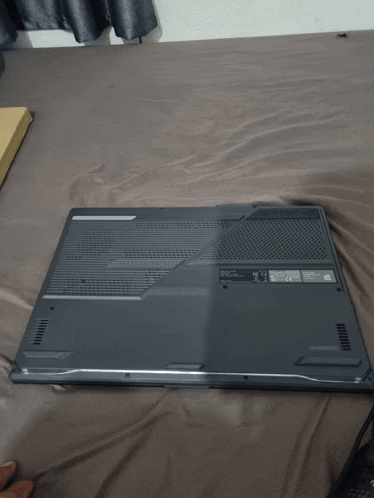 a laptop is laying on a bed and the back of the laptop has a sticker that says ' ce ' on it