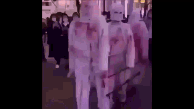 a group of people are standing in a line wearing masks and holding swords .