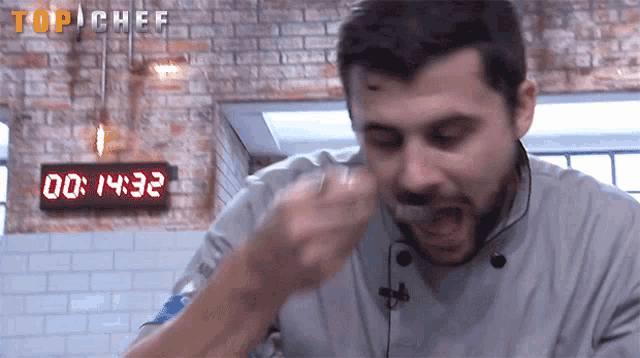 a man is eating something in front of a digital timer that reads 00 1432