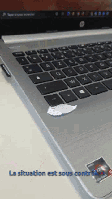 a silver laptop with a sticker on the keyboard that says la situation est sous contrition