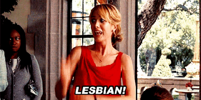 a woman in a red dress is saying lesbian in front of a window