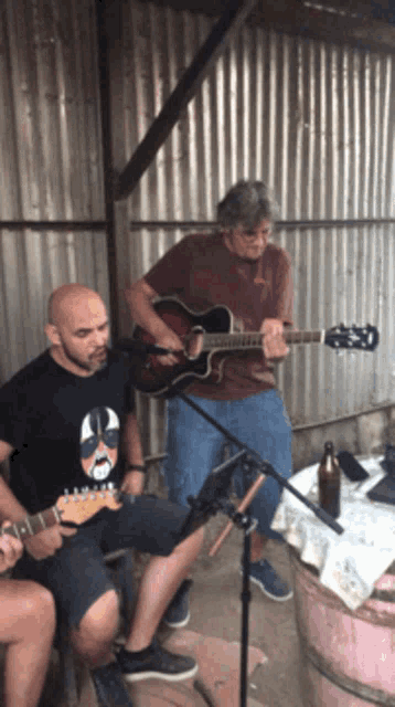 two men are playing guitars and one has a shirt that says kiss