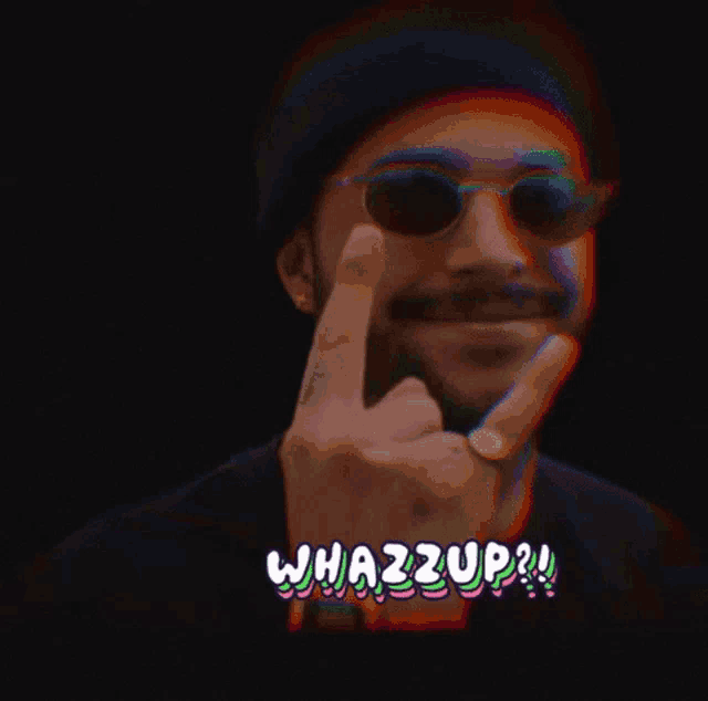 a man wearing sunglasses and a beanie giving the middle finger with the words whazzup written below him