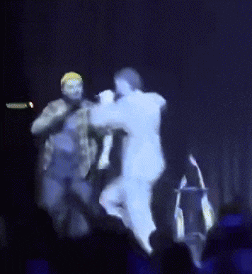 a blurry picture of a man singing into a microphone with a crowd watching