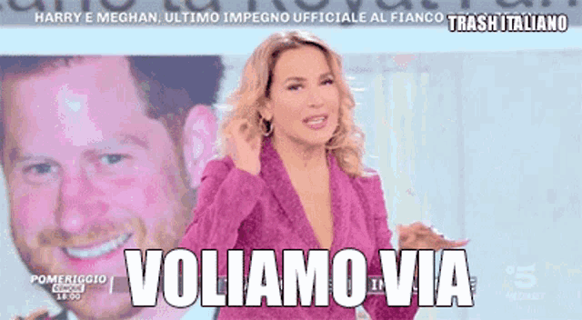 a woman in a pink jacket stands in front of a picture of harry and meghan and says voliamo via