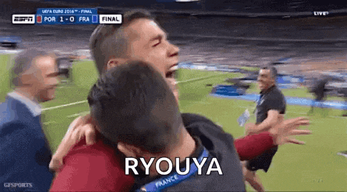a man is hugging another man on a soccer field with the word ryouya written on the bottom