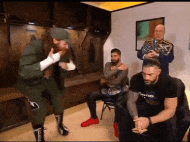 a group of wrestlers are standing in a room and one of them is wearing a shirt that says ' wrestling '