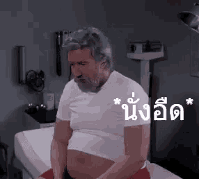a man with a beard and a pregnant belly is sitting on a bed in a doctor 's office .