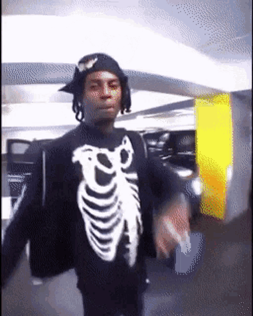a man wearing a skeleton sweater and a hat is dancing in a parking garage .