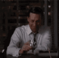 a man is sitting at a table drinking a glass of wine .