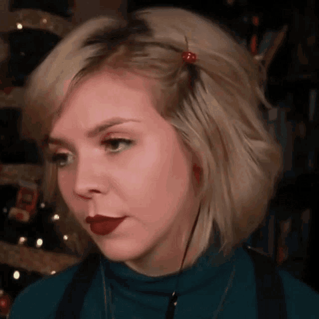 a close up of a woman 's face with red lipstick and a cherry in her hair