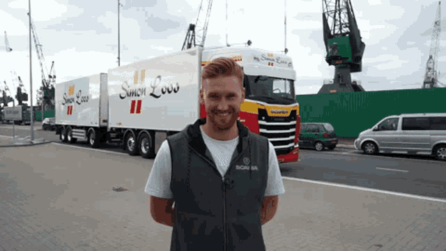 a man stands in front of a truck that says simon low