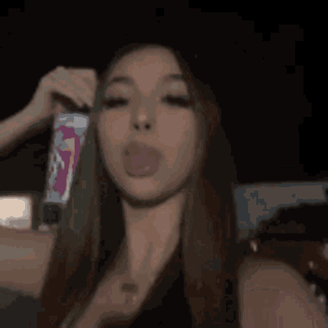 a woman is drinking a soda from a can .