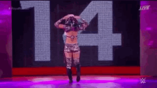 a female wrestler is standing on a stage in front of a large number .