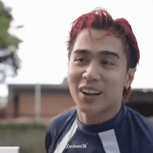 a man with red hair is smiling and wearing a blue shirt .