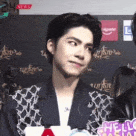 a young man in a suit is standing in front of a sign that says news .
