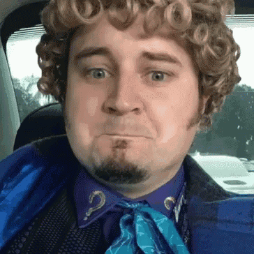 a man with curly hair and a beard is wearing a purple shirt with a question mark on the collar
