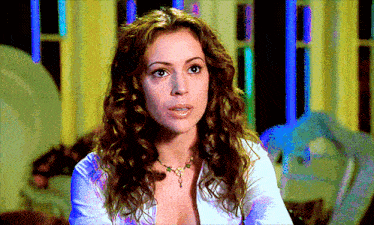 a woman with curly hair wearing a white shirt and a necklace