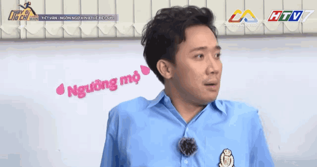 a man in a blue shirt is standing in front of a white board that says nguing mo