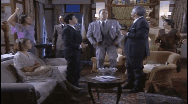a group of people are gathered in a living room and one man is holding a glass of wine
