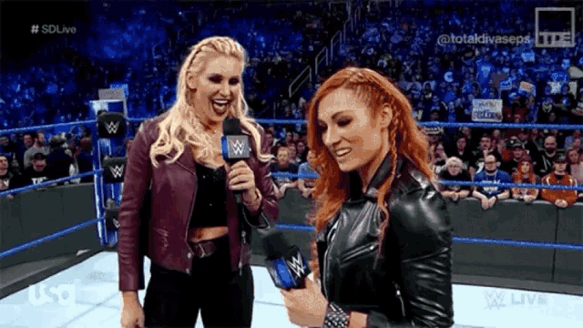 two women in a wrestling ring are laughing and talking into microphones with a sdlive logo in the background