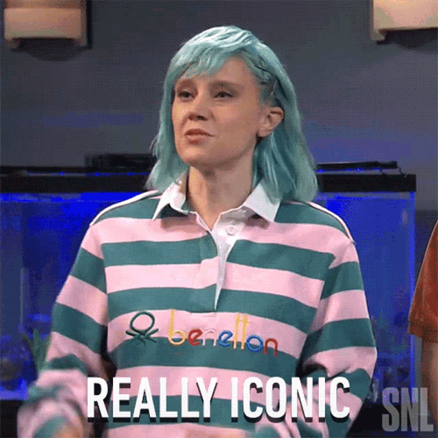 a woman with blue hair is wearing a shirt that says benetton