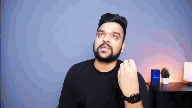 a man with a beard is wearing a black shirt and a smart watch