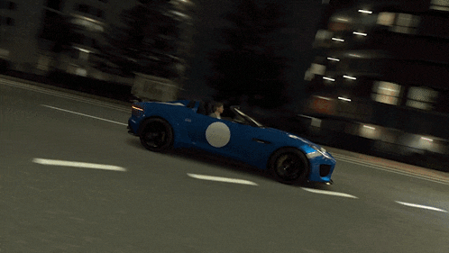 a blue sports car with a white circle on the side is driving down a road