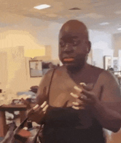 a man without a shirt is standing in a room holding a purse .