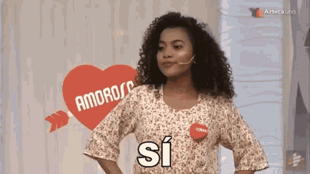 a woman wearing a shirt that says si is standing in front of a heart