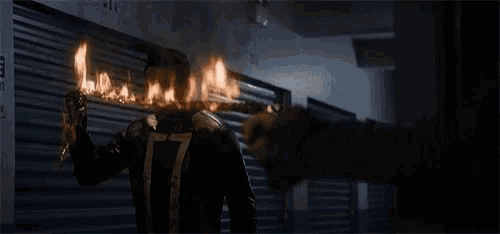 a person is holding a torch in a dark room and it is on fire .