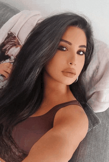 a woman with long black hair is laying on a couch with a blanket