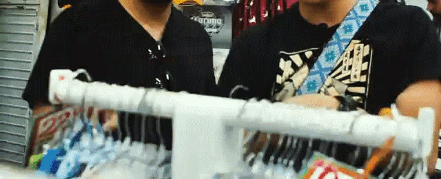 two men are looking at clothes in front of a corona cooler