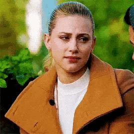 a woman wearing a brown coat and a white sweater is standing next to a man .