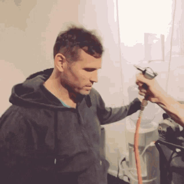 a man in a black hoodie is being sprayed with an air gun
