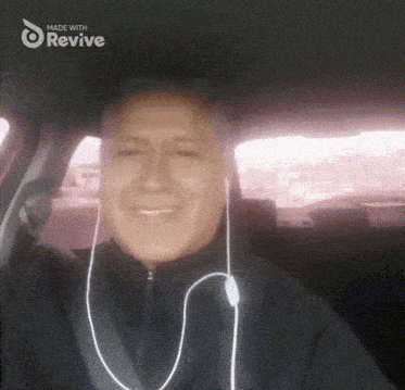 a man wearing ear buds in a car with the words made with revive above him
