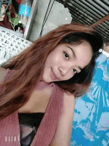 a woman with long hair is taking a selfie in front of a bottle of water .
